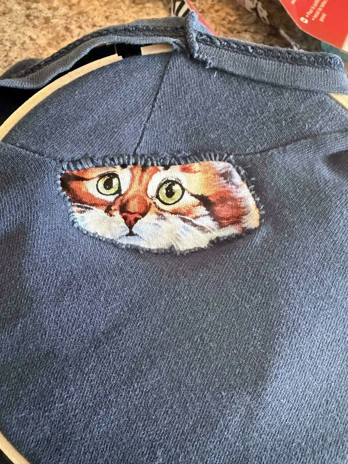Cat face fabric patch visible through a hole in blue clothing showing creativity to save money