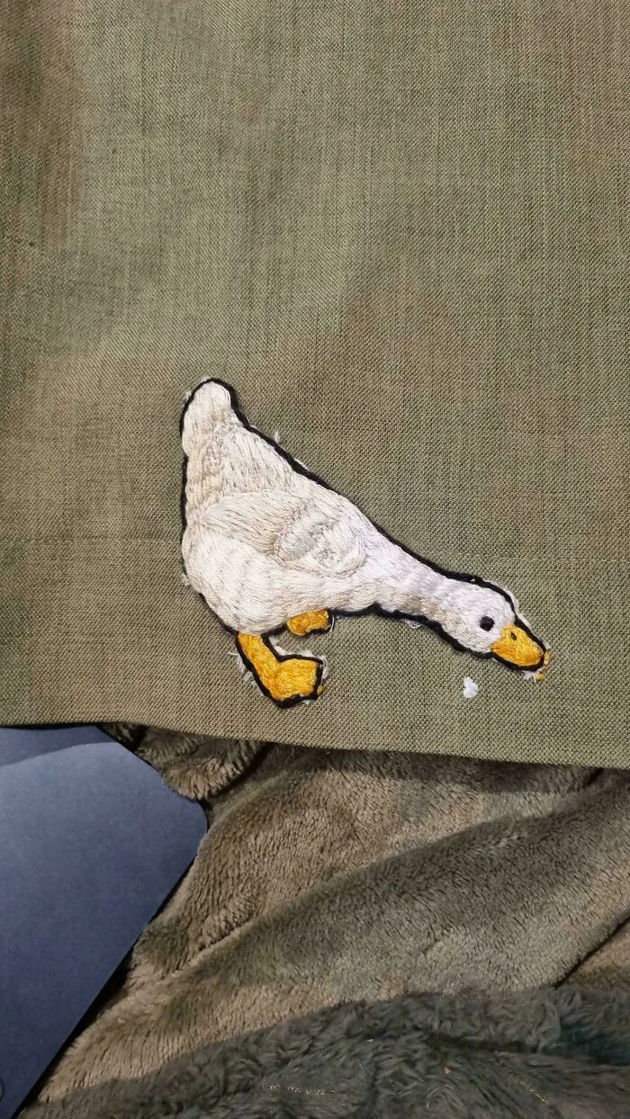 Embroidered white duck patch on olive fabric, illustrating how a little creativity saves money.