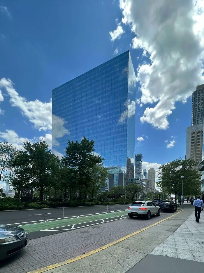 Reflective glass building showing a matrix glitch with sky and clouds reflection