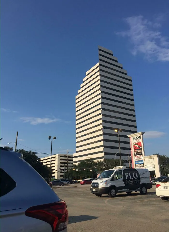 Tall building with striped windows in a city parking lot glitch