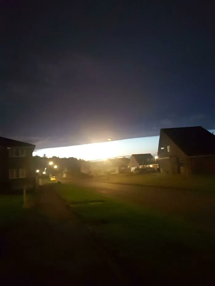 Unexpected bright light breaking through dark clouds over neighborhood resembling a matrix glitch