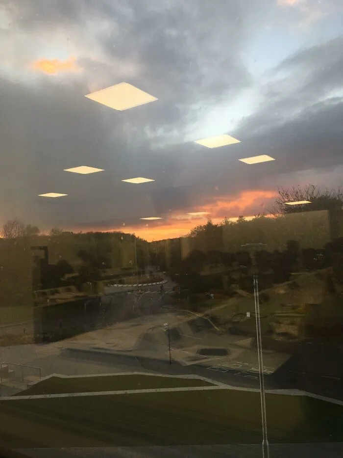 Reflection of glowing ceiling lights on window blending with sunset outside causing a matrix glitch effect