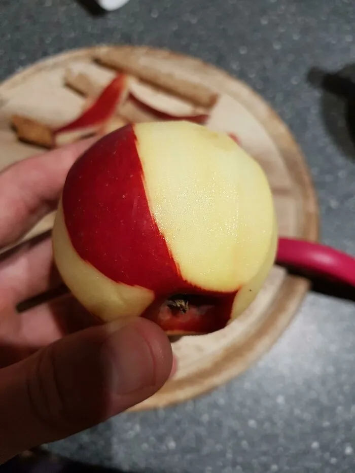 Hand holding a half-peeled red apple showing glitch-like pattern