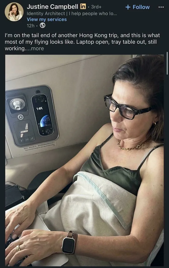 Woman working on laptop during flight with tray table down in airplane seat
