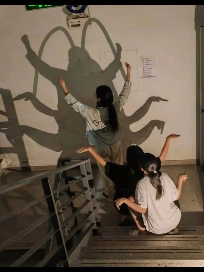 Weird photos of people making shadows that look like a giant bug on the wall.
