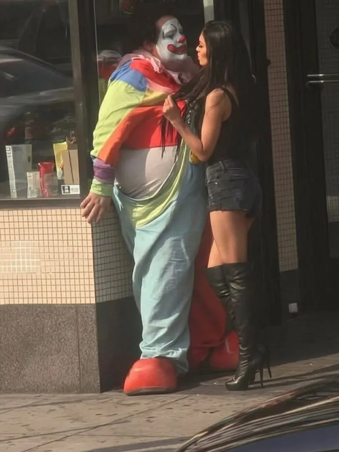 Weird and funny photos of a woman talking closely with someone in a clown costume.