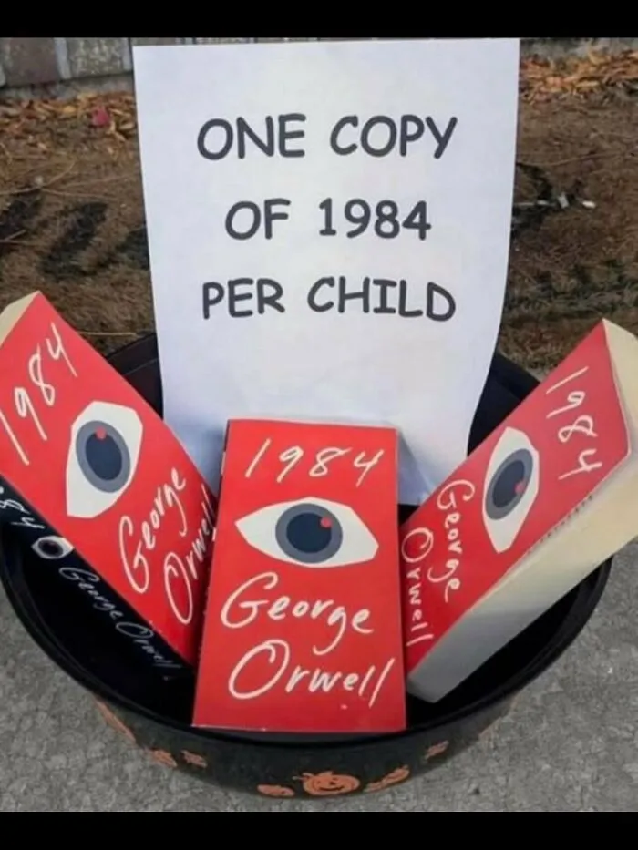 Halloween bucket with a sign reading One copy of 1984 per child filled with George Orwell books in weird random photos.