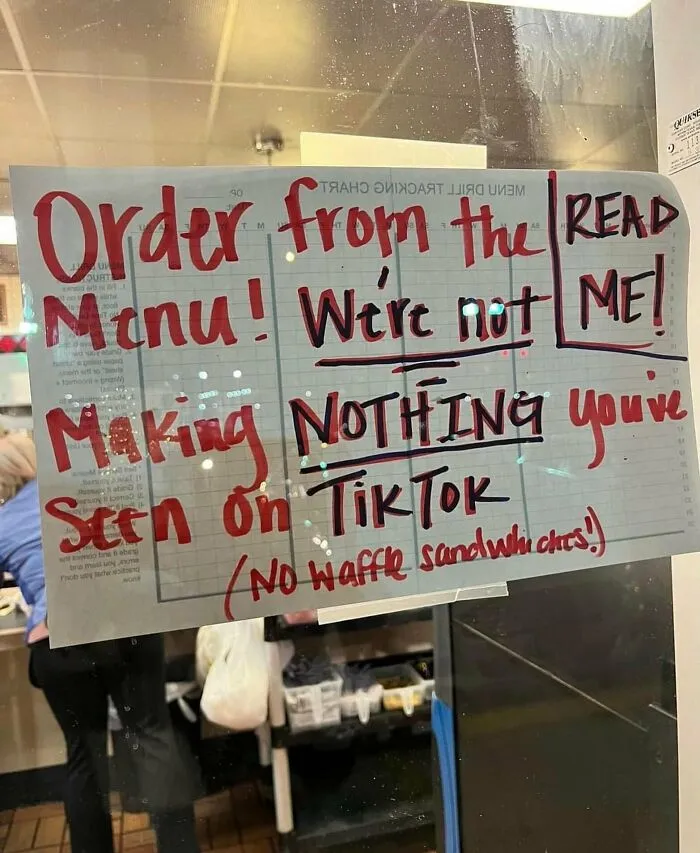Handwritten sign on a window instructing customers to order from the menu in weird and funny photos.