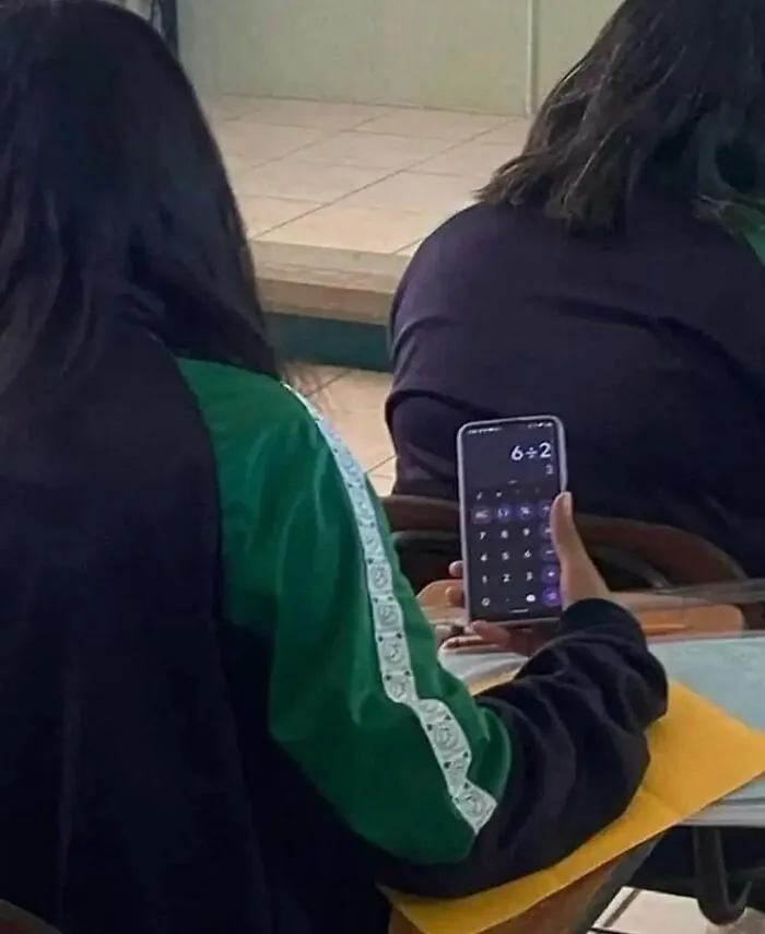 A student in class using a smartphone calculator for simple math, featured in funny random photos.