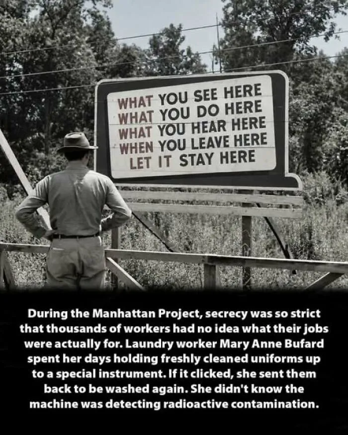 A man standing in front of a secrecy sign from the Manhattan Project, an interesting history moment.