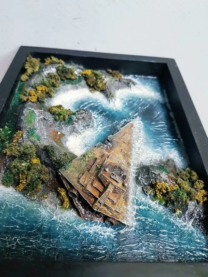 Miniature diorama of a pyramid structure surrounded by water and greenery