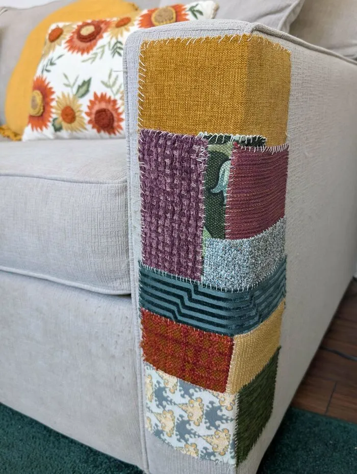 A couch arm patched with colorful fabric squares, an example of how creativity can save money.