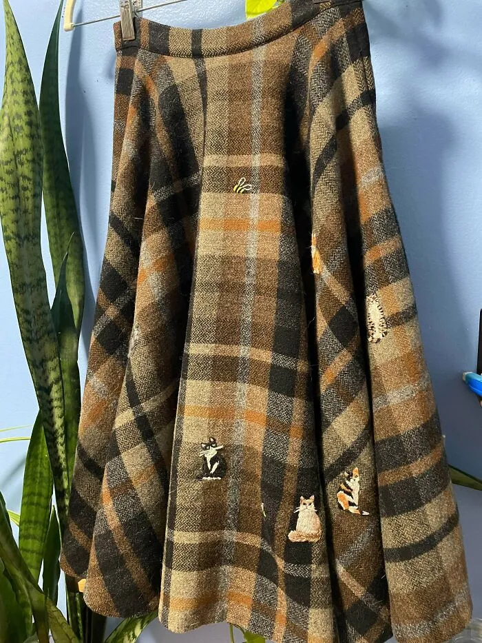 Plaid woolen skirt with small embroidered cats covering moth holes, proving creativity can save money.