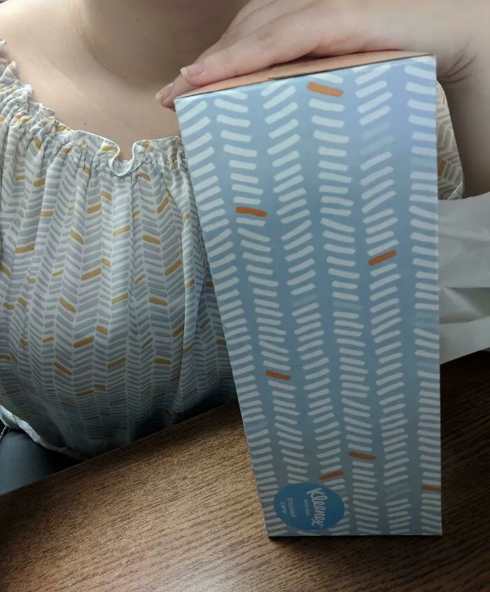 Person sitting with tissue box blending into patterned shirt matrix glitch