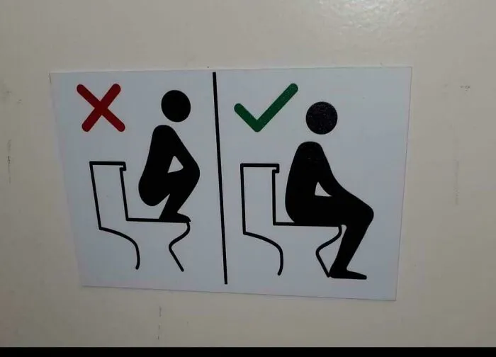 A restroom sign showing funny and confusing instructions on how to properly sit on a toilet.