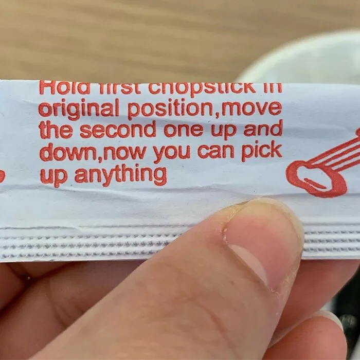 A close-up of a chopstick wrapper with confusing instructions printed in red text