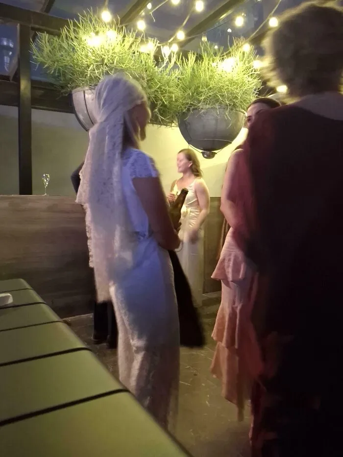 Bridal party mingling under hanging plants and string lights at wedding reception
