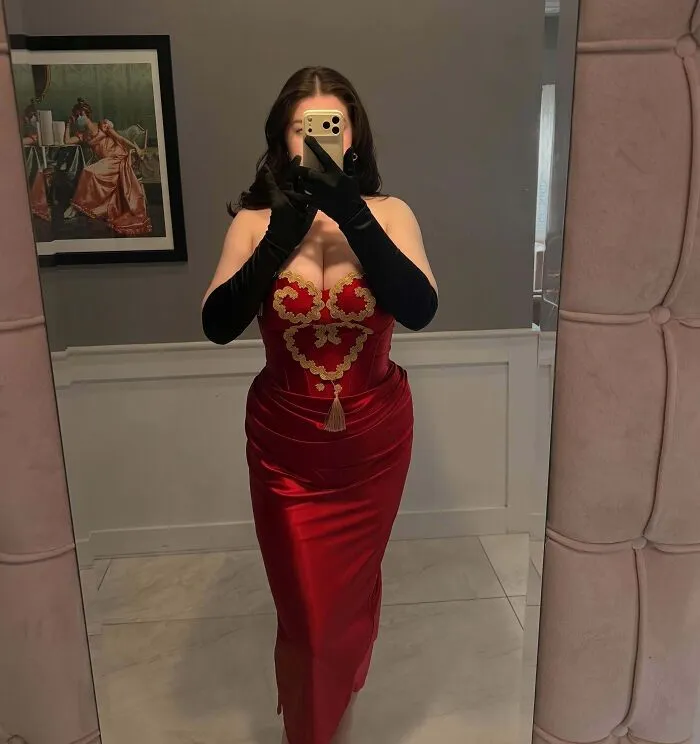 Woman in red dress taking selfie in mirror before wedding event