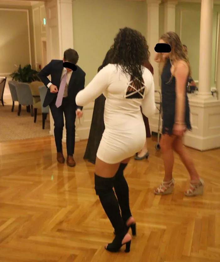 Wedding party dancing indoors with woman in short white dress and thigh-high boots