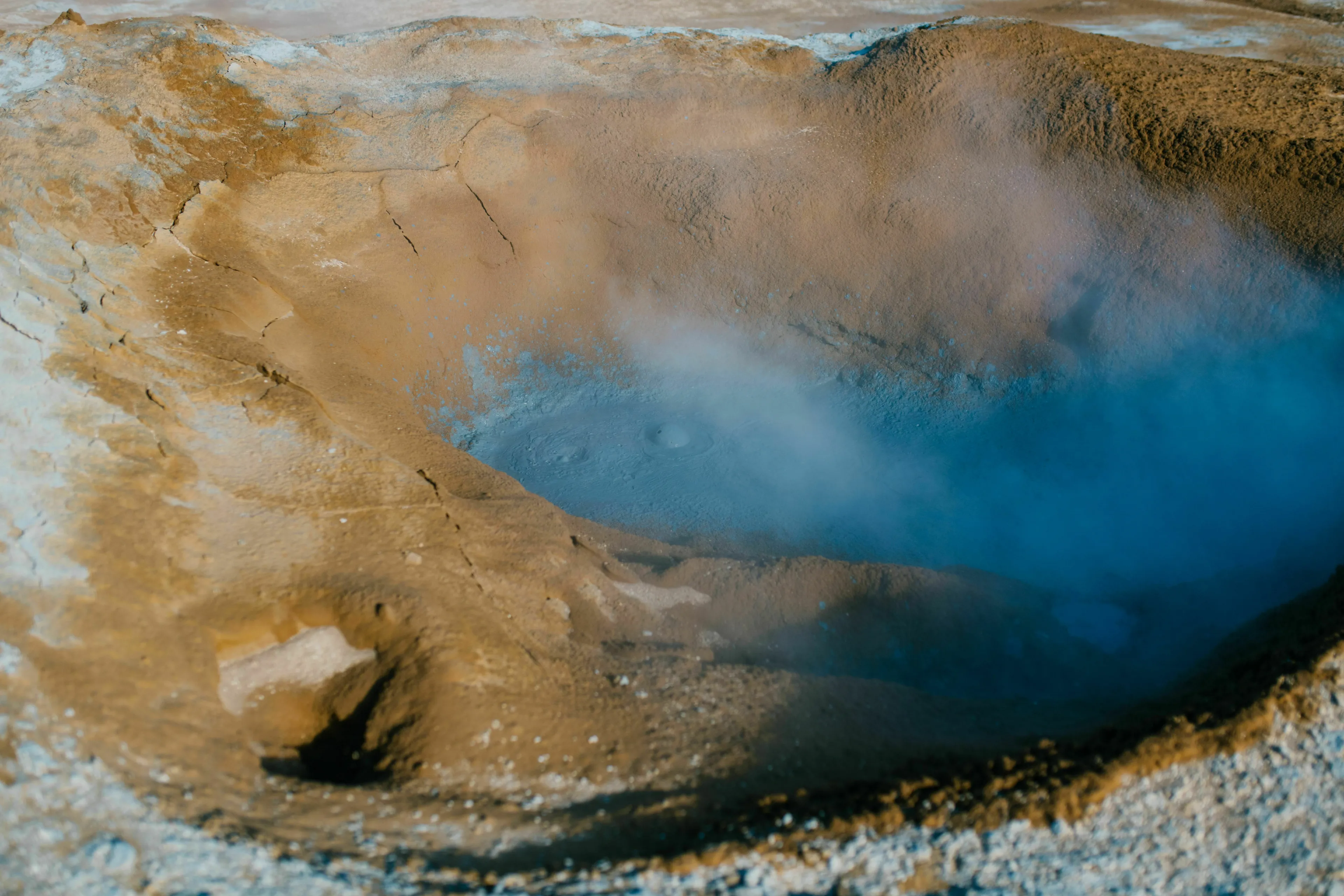 Geothermal hot spring steaming in a rugged landscape with earth tones