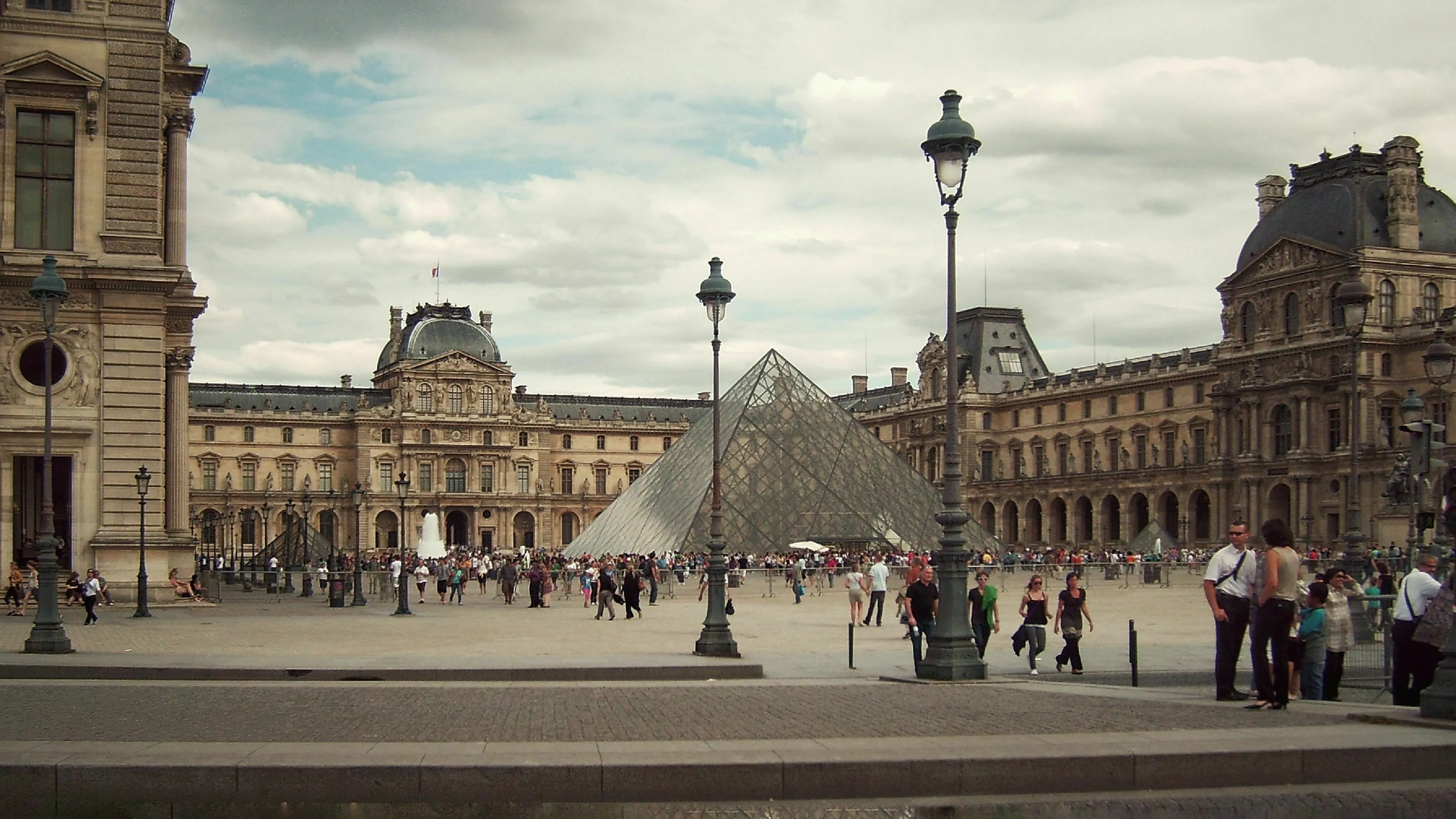 Paris Louvre Museum courtyard with glass pyramid and historic buildings