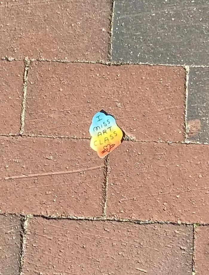 A colourful sticker on the pavement reading I miss art class, showcasing found paper.