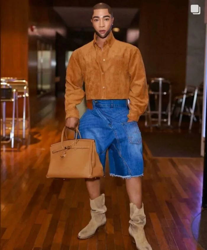 Ridiculously edited photo of a man wearing unusual combination of cropped pants and boots indoors