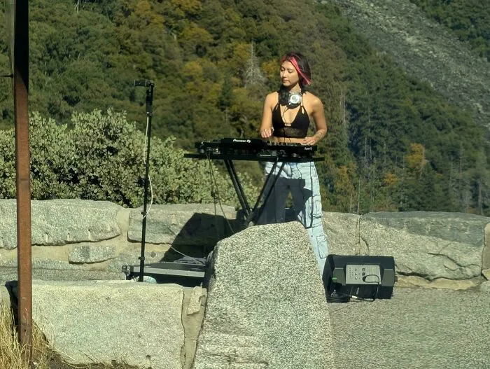 Influencers in public spaces setting up DJ equipment and recording content outdoors in a scenic mountain park