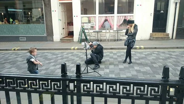 Influencers in public spaces taking professional photos with camera equipment on a city street
