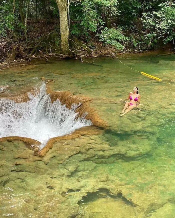 Influencers in public spaces relaxing in natural water near a small waterfall