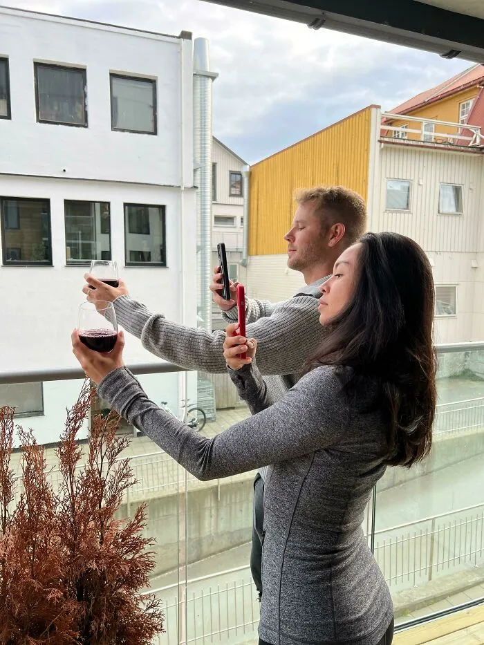 Influencers in public spaces taking photos of red wine glasses on a balcony