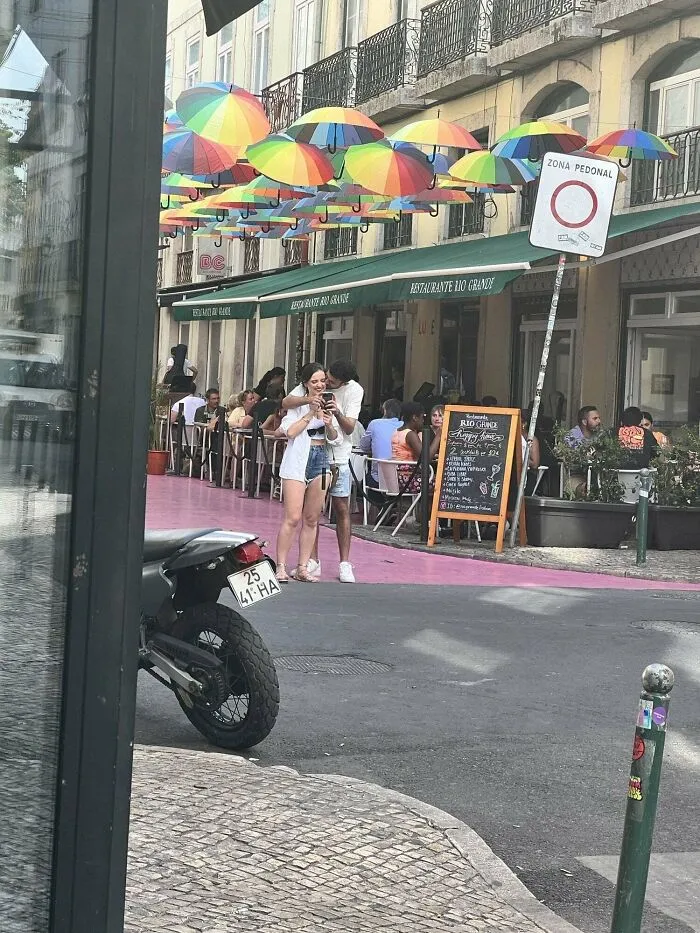 Influencers in public spaces posing for a photo on a street under colorful umbrellas