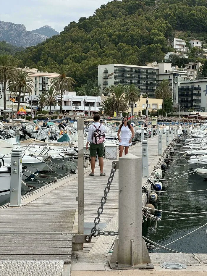 Influencers in public spaces posing for photos on a wooden pier full of boats.