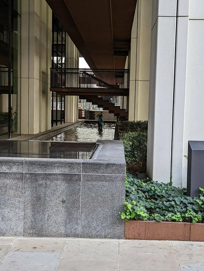 Person standing in an urban fountain using public spaces as a personal content studio