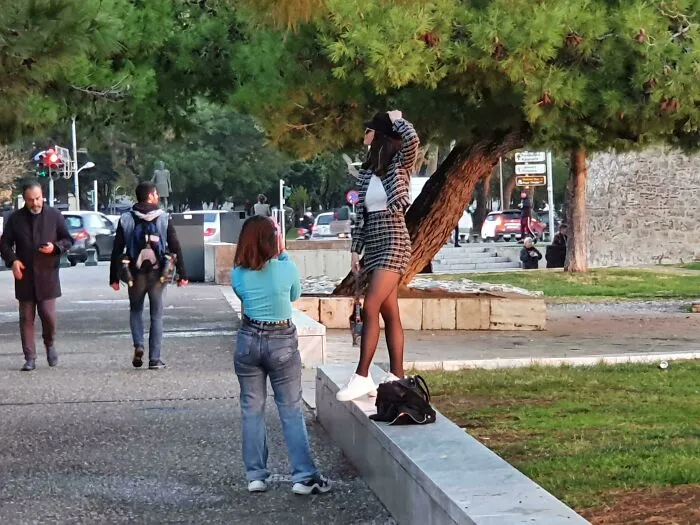 Woman in plaid outfit posing in public spaces while someone takes photos.