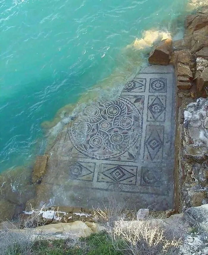 Submerged ancient Roman mosaic floor partially covered by clear turquoise water, showcasing surprising facts about the past.