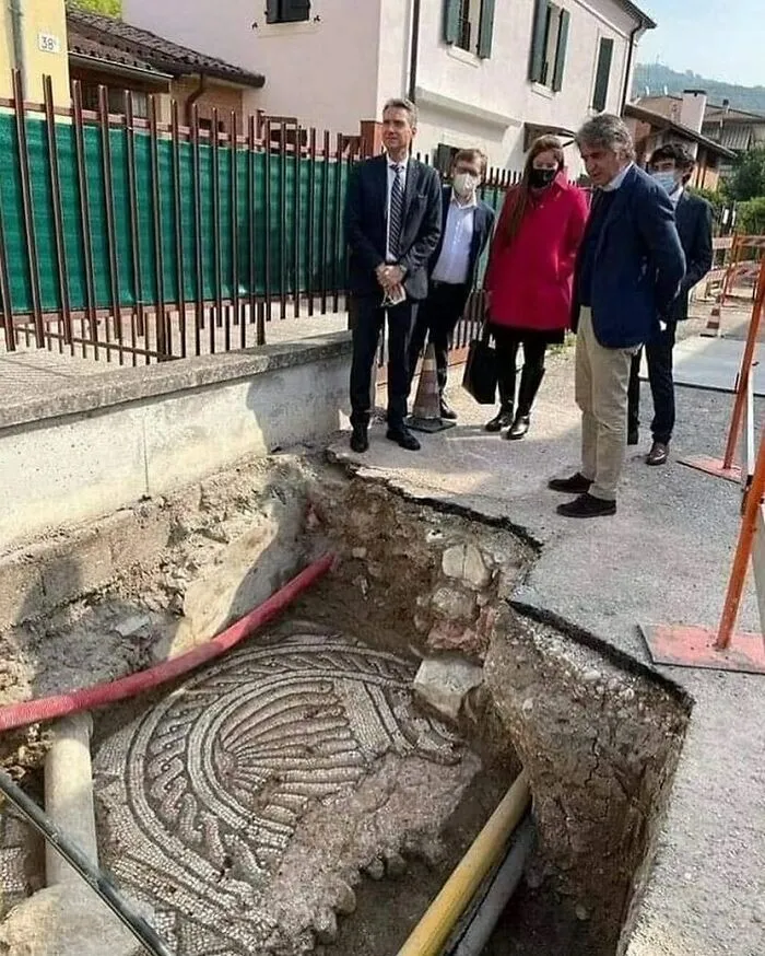 People observing an ancient Roman mosaic floor uncovered underground, highlighting facts about the past.