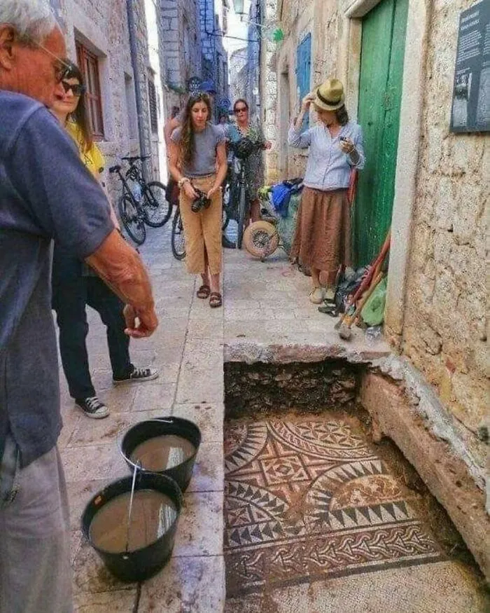 People admiring an ancient floor mosaic uncovered during excavations, revealing cool history facts.