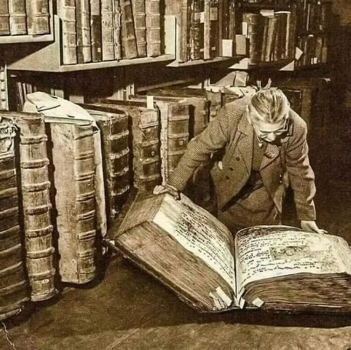 A woman looking through a giant antique book in a library filled with old tomes, displaying facts about the past.