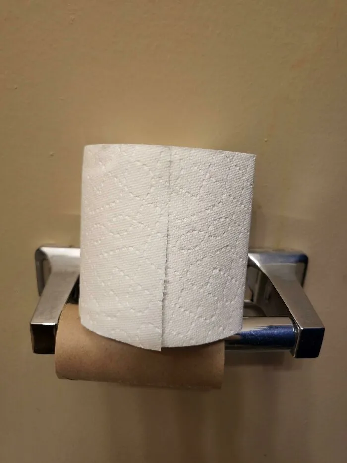 An fresh toilet paper roll stacked directly on top of an empty roll on a holder.