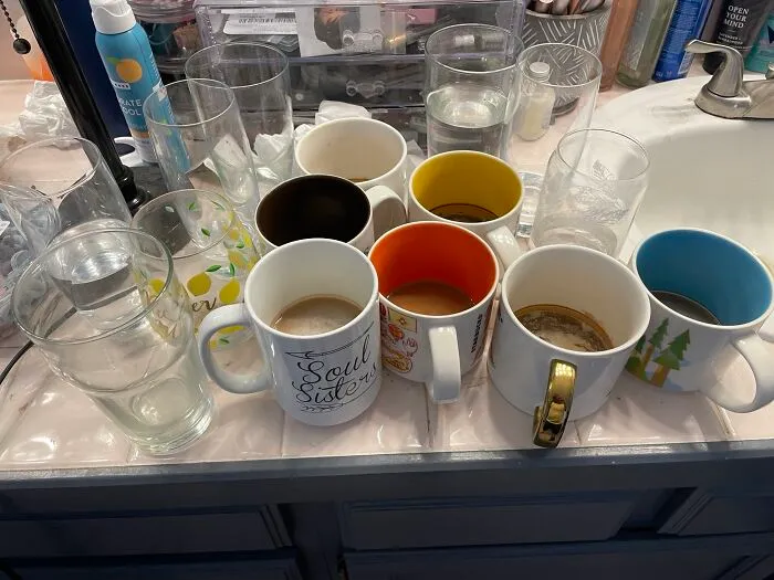 A bathroom counter cluttered with dirty coffee mugs and glasses that drive people insane.