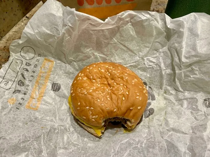 A bitten hamburger wrapped in paper showing annoying things partners do.
