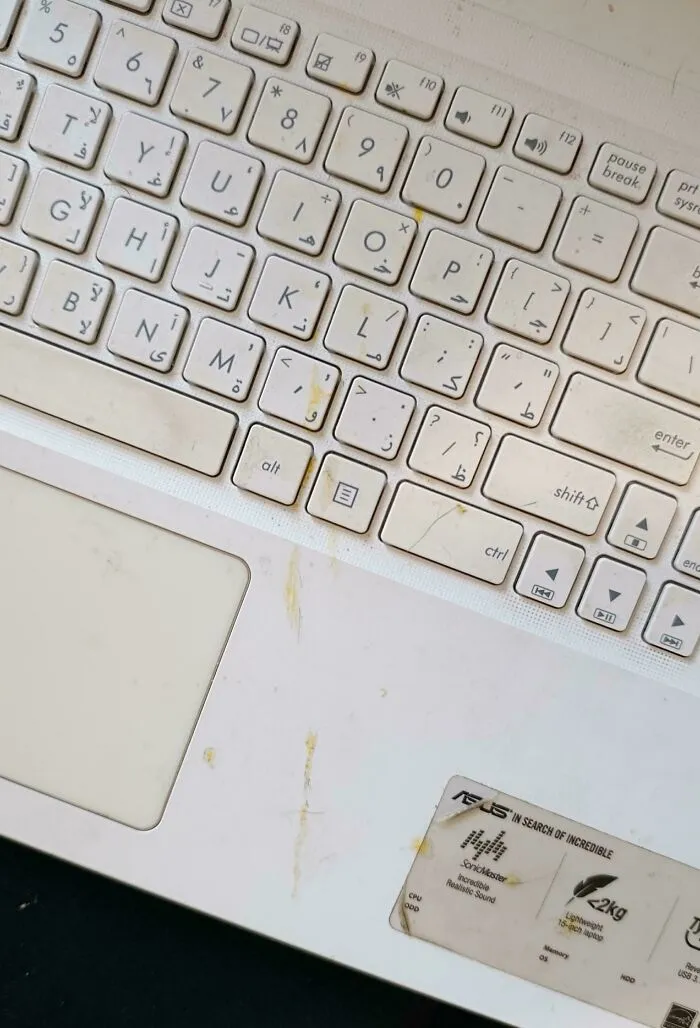 Dirty white laptop keyboard covered in stains, showing annoying things partners do at home.