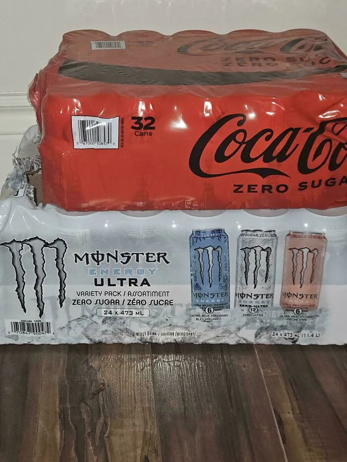 Heavy pack of Coca-Cola Zero Sugar precariously balanced on top of a soft Monster Energy drink box.