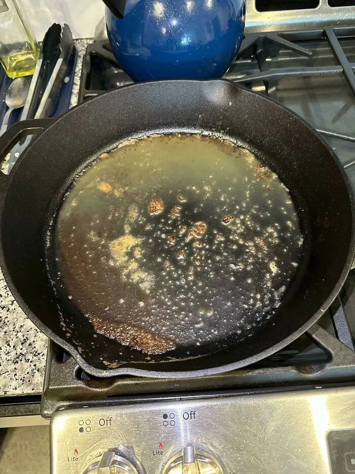 A dirty cast iron skillet with grease left on a stove, showing annoying things partners do.