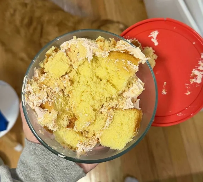 A glass container filled with smashed yellow cake, showing things partners do that drive people insane.