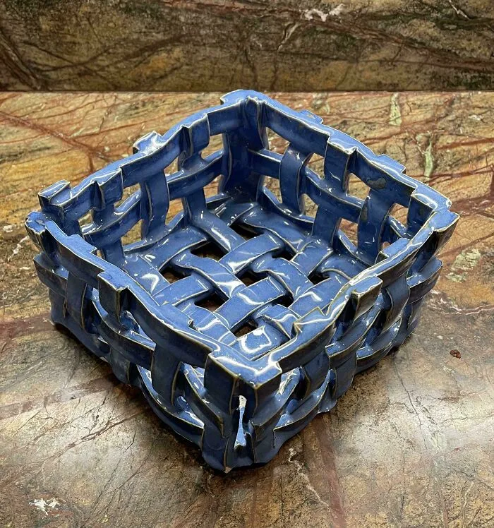 Handcrafted blue woven ceramic basket showcasing unique pottery creations on a marble surface