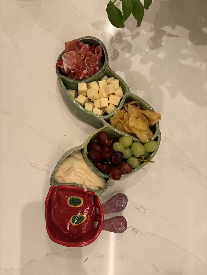 Caterpillar-shaped ceramic serving dish with snacks, an example of creative pottery creations