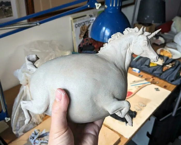 Hand sculpting a chunky clay unicorn figure as part of creative pottery creations.