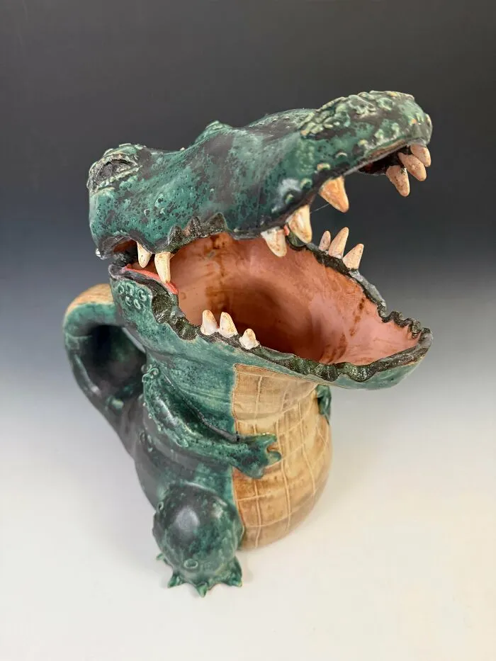 A hand sculpted green alligator mug showcasing unique pottery creations